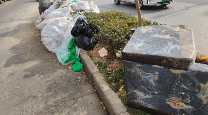 华商记者帮||西安科技二路沙井村外，绿化带内堆着袋装生活垃圾